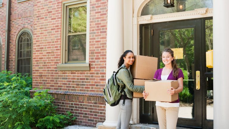 Image of two girls holding boxes outside dormitory